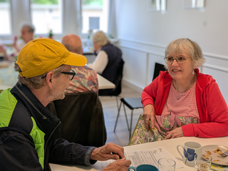Besucher und Besucherin unterhalten sich an einem Tisch